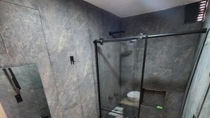 A modern bathroom with a glass shower enclosure, a white toilet, and a wooden vanity with a sink.