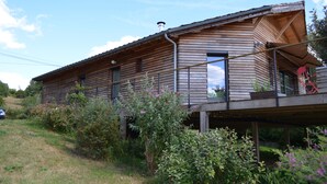 A wooden house with a balcony, surrounded by greenery. - Modern house, 3 bedrooms, large quiet terrace, near Rocamadour, Dordogne... (Puybrun)