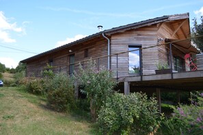 A wooden house with a balcony, surrounded by greenery. - Modern house, 3 bedrooms, large quiet terrace, near Rocamadour, Dordogne... (Puybrun)