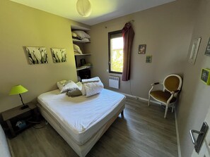 A bedroom with a bed, a chair, a window with curtains, a lamp, and wall art. - Modern house, 3 bedrooms, large quiet terrace, near Rocamadour, Dordogne... (Puybrun)