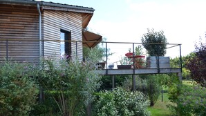 Ein Holzhaus mit Balkon, umgeben von üppiger Bepflanzung und einem Garten.