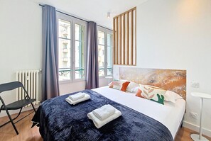 Ein Hotelzimmer mit Bett, Stuhl, Heizkörper und einem fenster mit Vorhängen.