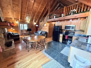 Ein Holzblockhaus-Interieur mit Essbereich, Küche und Wohnzimmer.