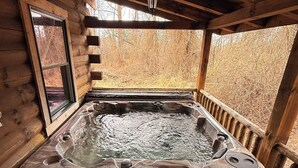 Une cabane en bois avec un bain à remous et un banc.