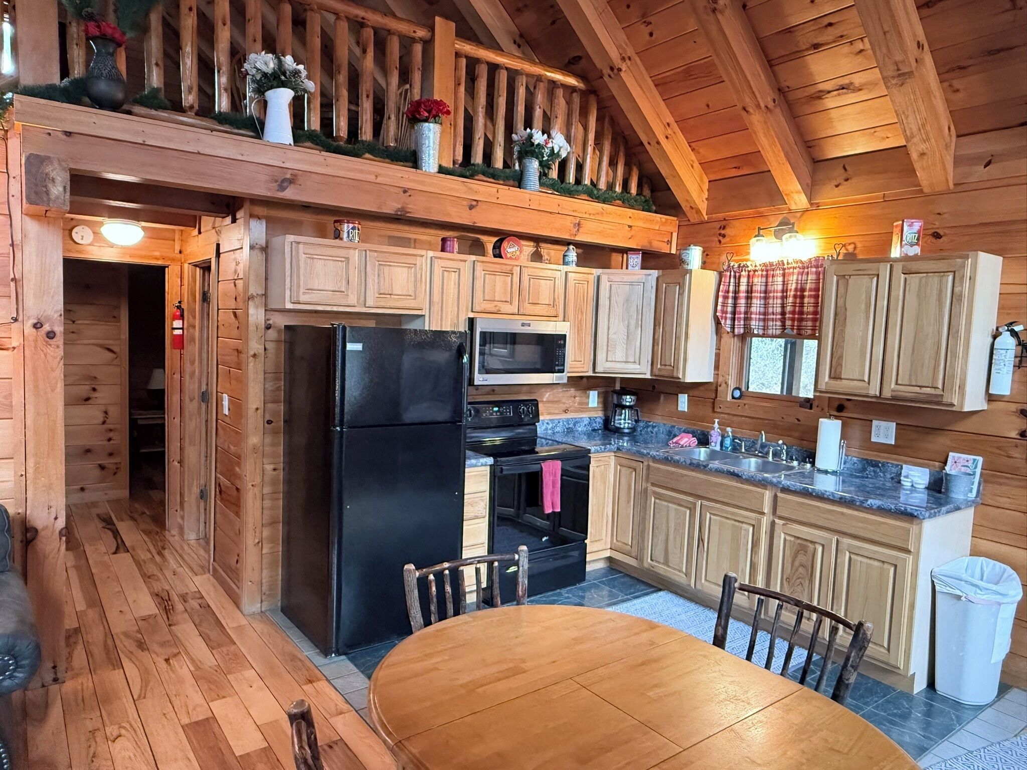 A wooden cabin kitchen with a refrigerator, stove, microwave, and wooden cabinets.