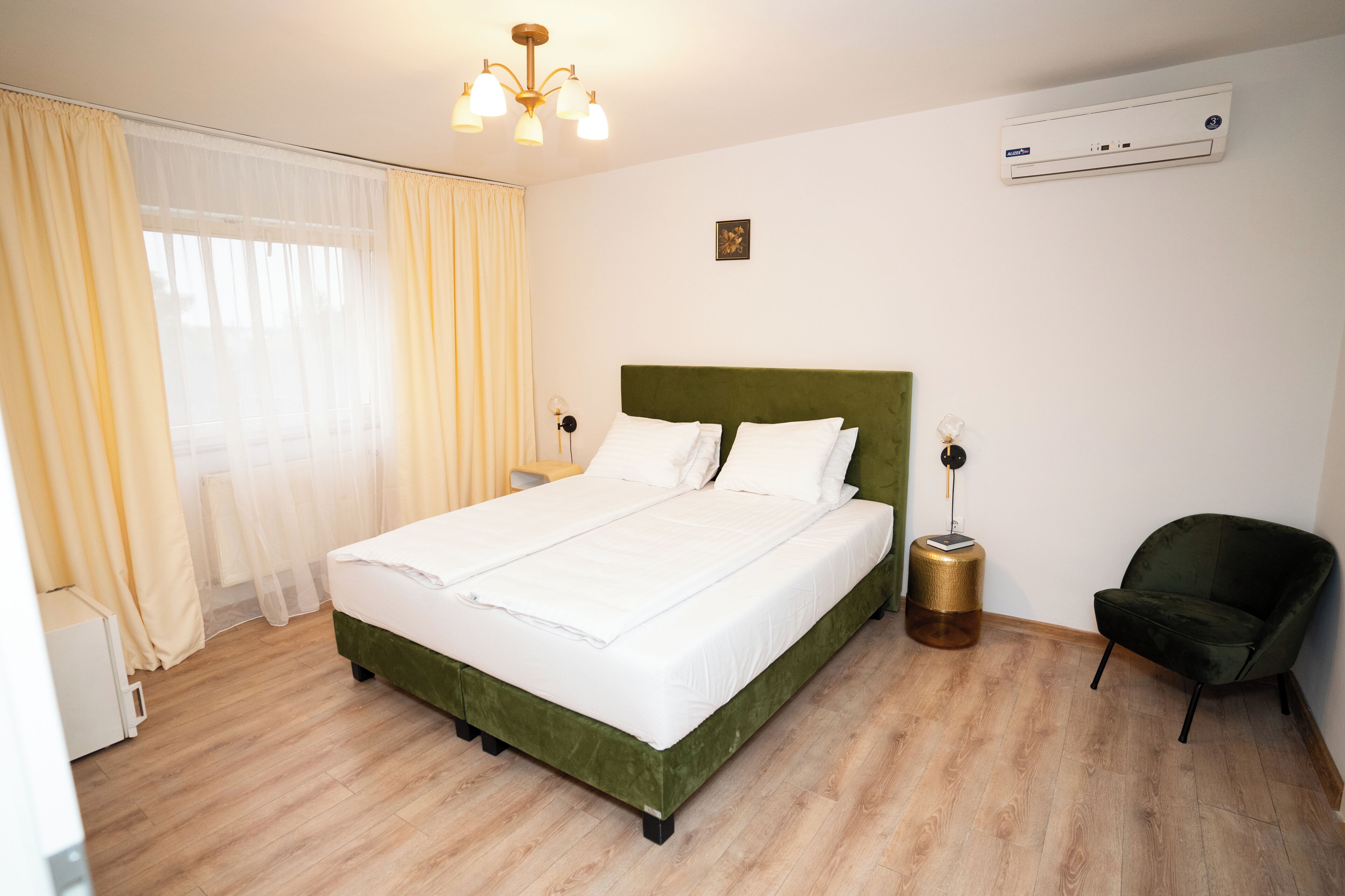 Habitación de hotel con cama, una silla, mesita de noche, lámpara y aire acondicionado.