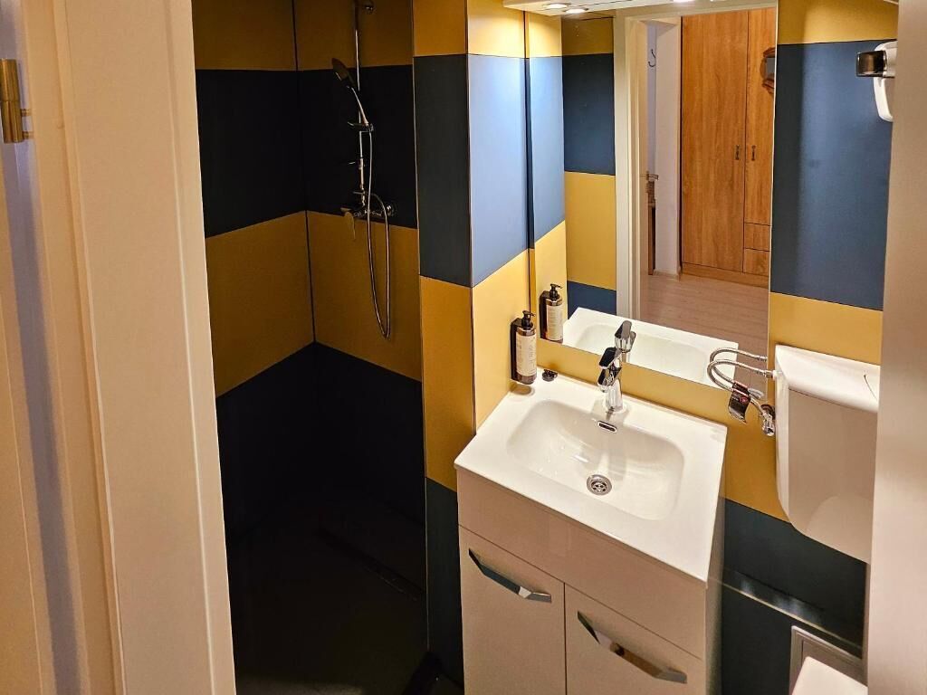 Un bagno con doccia, lavandino e specchio.