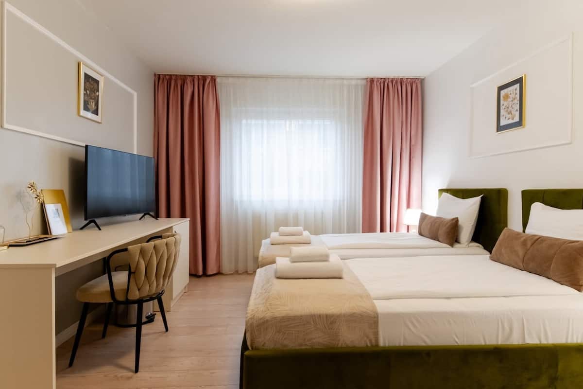 Une chambre d’hôtel équipée d’un bureau, de deux lits, d’une chaise et d’un téléviseur.