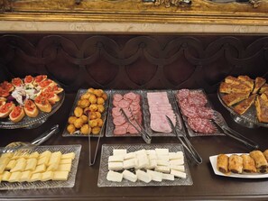 Ein reichhaltiges Buffet mit verschiedenen Speisen, darunter Brot, Käse und Fleischwaren.