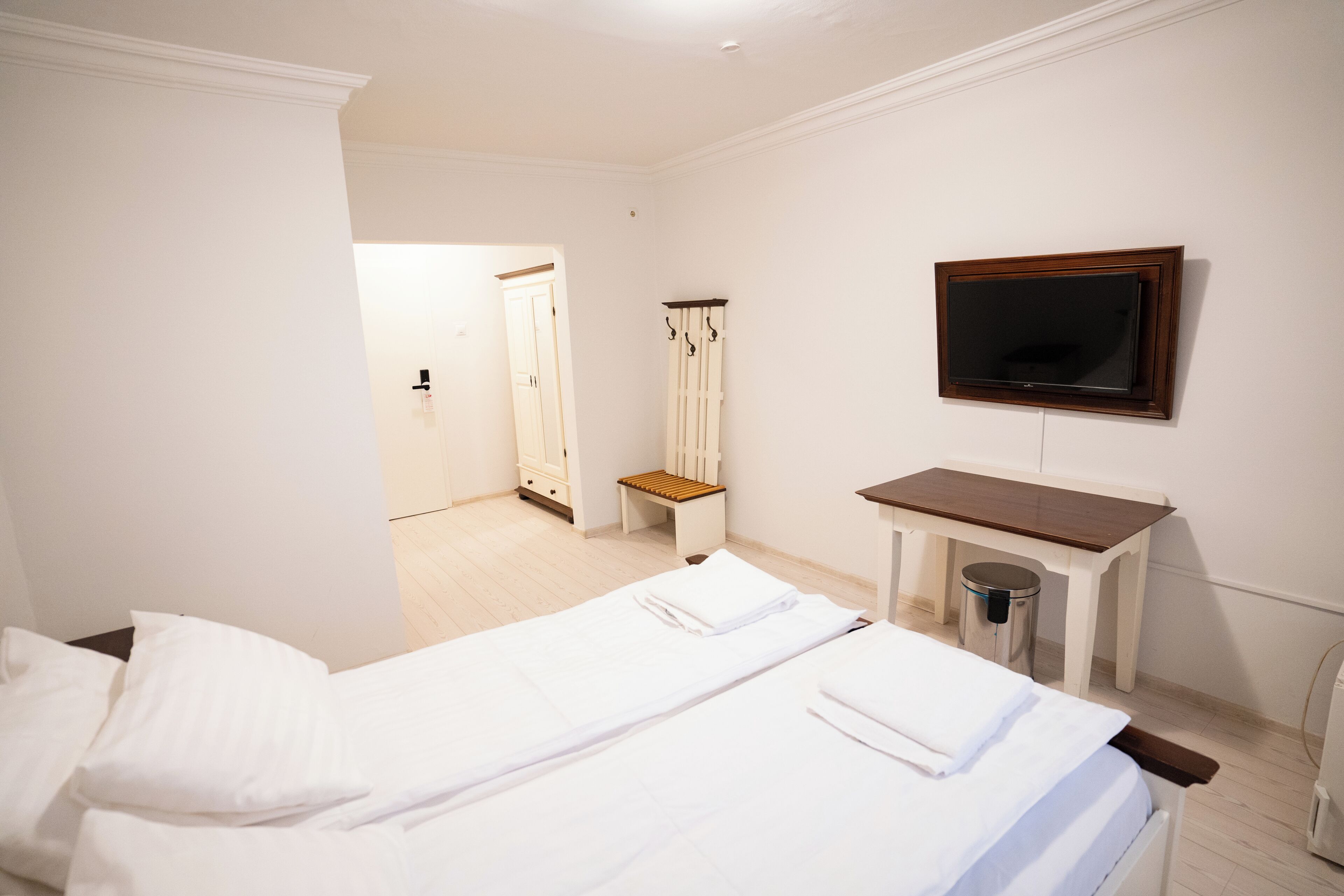 A hotel room with two beds, a TV, a desk, a chair, and a wardrobe.