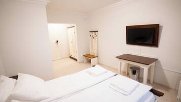 A hotel room with two beds, a TV, a desk, a chair, and a wardrobe.