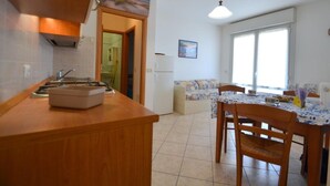 A kitchen with a countertop, sink, and a dining area with a table and chairs. - Cozy Holiday Escape With Relaxing Terrace (San Michele al Tagliamento)