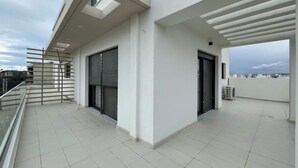Ein modernes Gebäude mit flachem Dach, großen Fenstern und einem Balkon mit Metallgeländer.