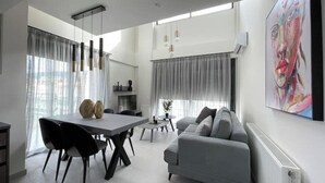 Ein modernes Wohnzimmer mit Essbereich, grauem Sofa und einem großen Gemälde an der Wand.