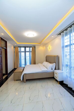Ein Hotelzimmer mit Bett, Nachttisch und Blick durch das Fenster.