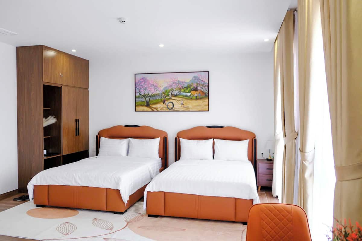 A bedroom with two beds, a wardrobe, a painting, and a chair.