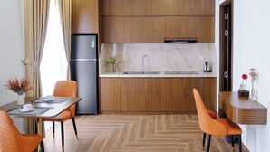 A modern kitchen with wooden cabinetry, a stainless steel refrigerator, and a marble countertop. - KHEM BEACH HOTEL (An Thoi)