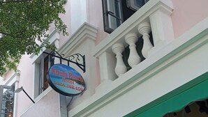A hotel sign with contact information, a restaurant sign advertising a dish, and a building facade with a green awning and arched windows. - KHEM BEACH HOTEL (An Thoi)