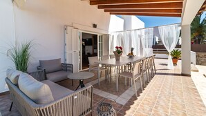 Un patio al aire libre con un sofá, una mesa, sillas y plantas en macetas.