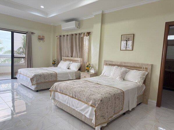 A hotel room with two beds, a balcony, and an air conditioning unit.