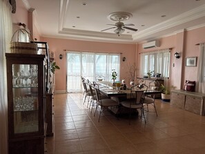 A dining area with a table set for four, surrounded by chairs, a ceiling fan, and a cabinet with glassware. - A secluded stunning villa by the beach. (Carmen)