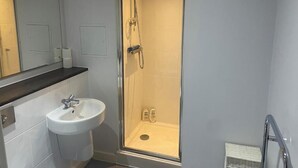 A bathroom with a glass-enclosed shower, a white sink, and a mirror. - Radio City Apartments near City Centre (Liverpool)