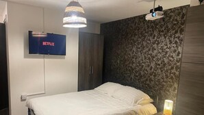 A bedroom with a bed, a TV mounted on the wall, a wardrobe, and a bedside lamp. - Radio City Apartments near City Centre (Liverpool)