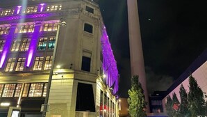 A building with 'FLANNELS' signage, a tall tower with colorful lights, and a modern structure with a flat roof. - Radio City Apartments near City Centre (Liverpool)