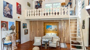 Une chambre avec un lit en mezzanine, un plancher en bois et un balcon agrémenté d’objets décoratifs.
