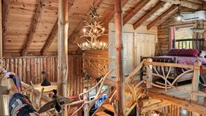 L’intérieur d’un chalet rustique, avec un escalier en bois, un lustre et un lit.