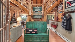 L’intérieur d’un chalet rustique, avec un banc vert, des murs en bois et un panneau indicateur indiquant les directions des sentiers.