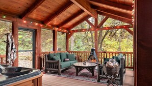 Une terrasse en bois avec un jacuzzi, un foyer extérieur et des sièges pour profiter de l’extérieur.