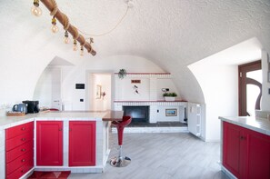 Une cuisine avec une cheminée, des armoires rouges et un luminaire suspendu.