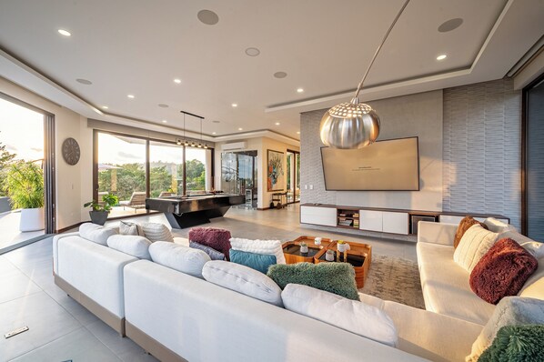 A modern living room with a pool table, a sofa set, a TV, and a large window. - Vida Mar Ocean View Near Jaco & Beach (Playa Hermosa)