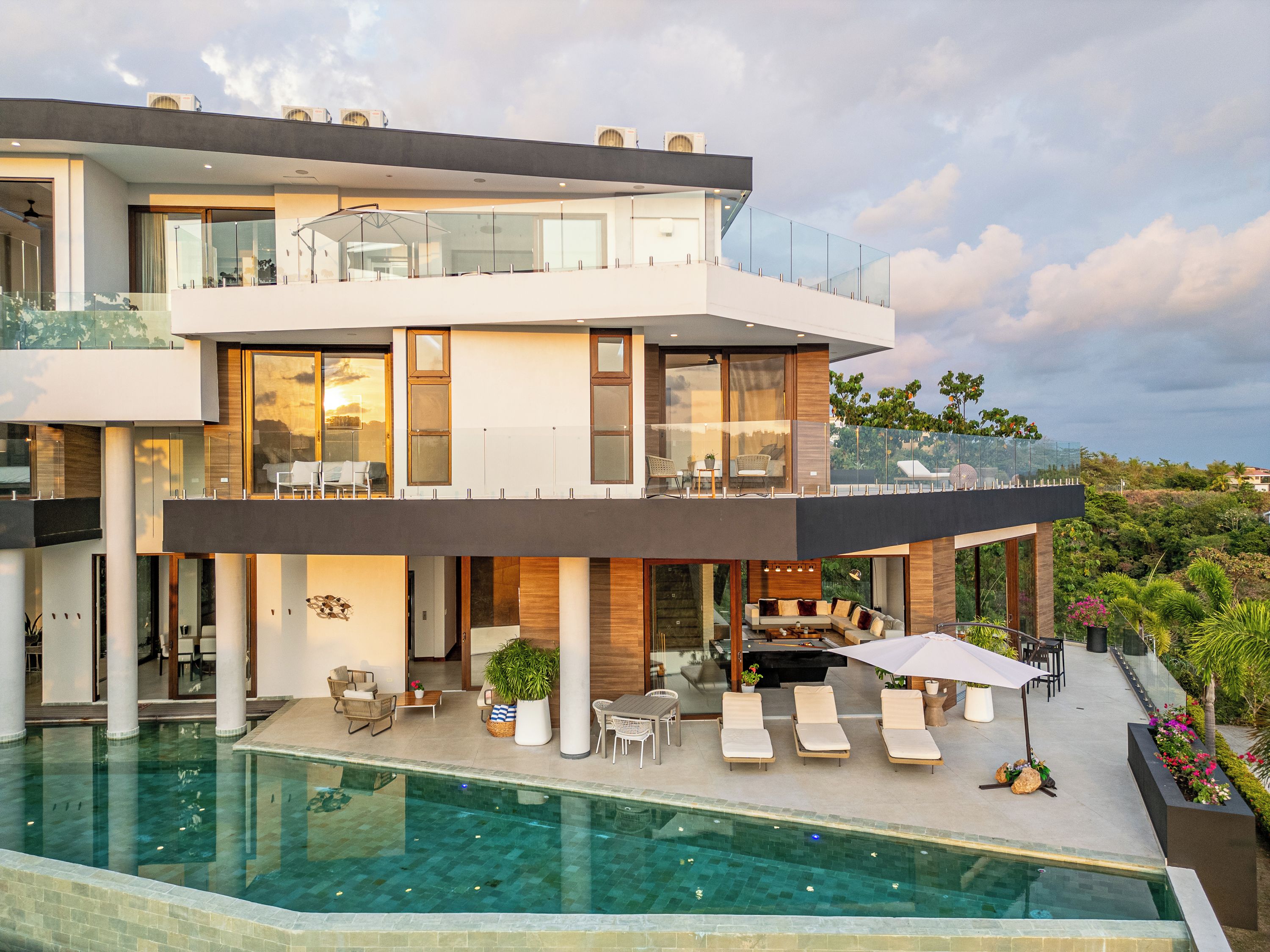 A modern two-story house with a rooftop terrace, a swimming pool, and outdoor seating.
