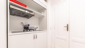 A white kitchen with a built-in microwave, a small sink, and a utensil holder. - La Casa di Lidia - Vatican City  (Rome)