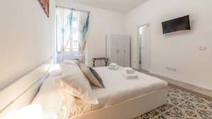 A bedroom with a bed, a TV, a wardrobe, and a window with curtains. - La Casa di Lidia - Vatican City  (Rome)
