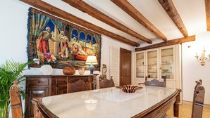 A dining area with a large table, wooden chairs, a chandelier, and a decorative tapestry. - CA MANDORLA (Venezia)