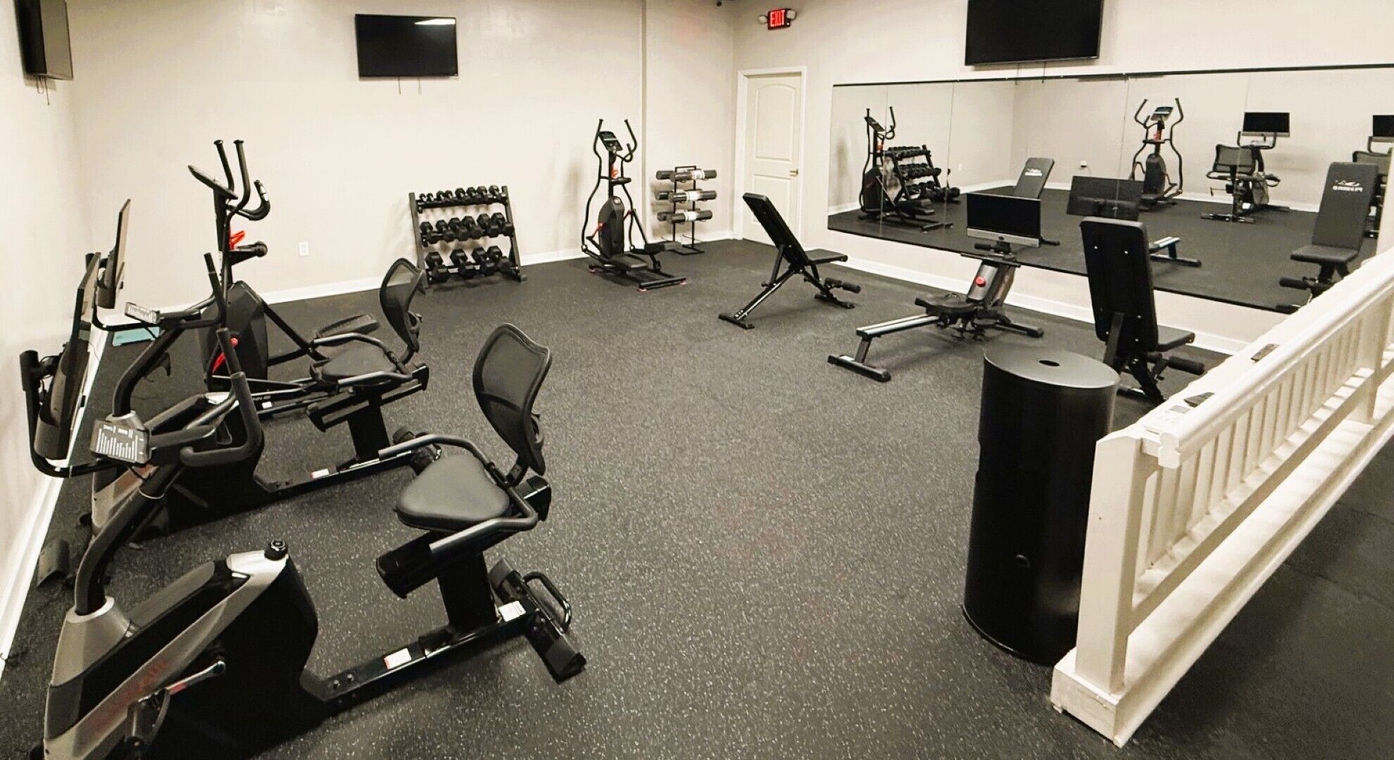 Une salle de sport équipée de divers appareils d’exercice, notamment des tapis de course, des vélos d’appartement et des appareils de musculation.