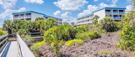 A resort with two-story buildings, a wooden boardwalk, and a variety of tropical vegetation.