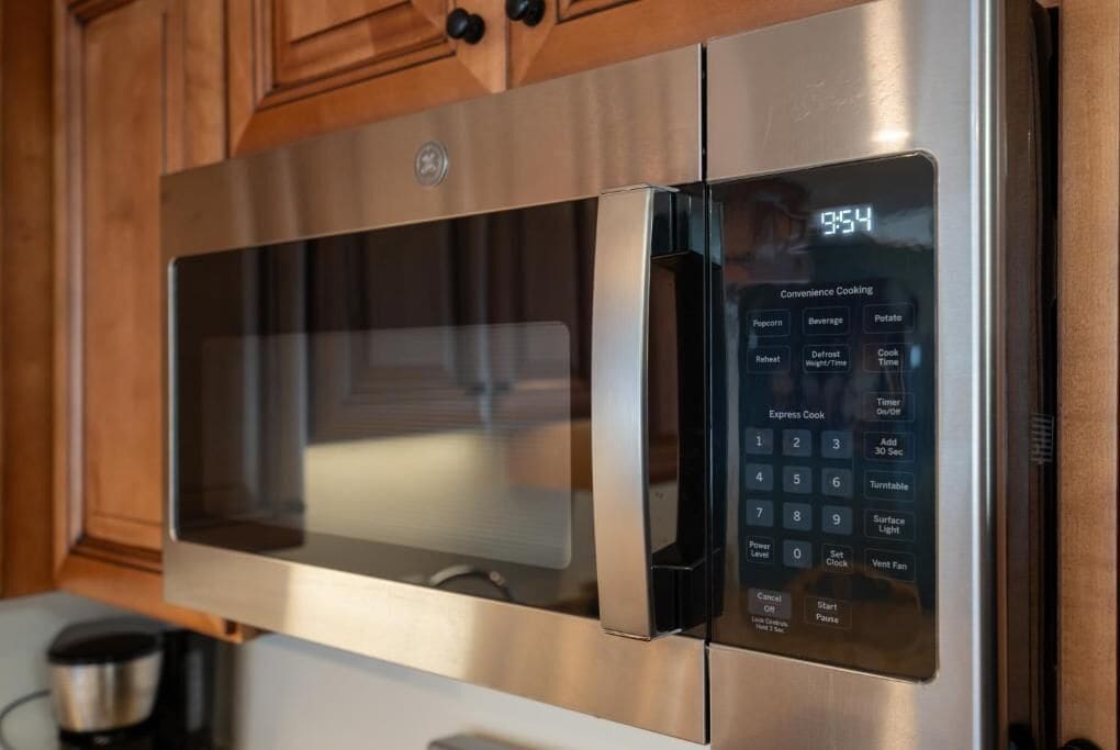 A modern kitchen with a stainless steel microwave oven, a digital display, and a control panel with various cooking options.