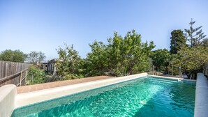 A swimming pool with clear blue water, surrounded by a wooden fence and trees. - Rural House 'Sa Caseta Mallorca Studio' with Mountain Views, Shared Pool and Wi-Fi (Algaida)