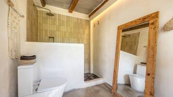 Ein Badezimmer mit einer weißen Toilette, einem spiegelnden Holzrahmen und einer Duschkabine.