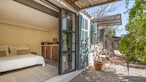 A bedroom with a bed, a nightstand, and a window with a view of the outside. - Rural House 'Sa Caseta Mallorca Studio' with Mountain Views, Shared Pool and Wi-Fi (Algaida)