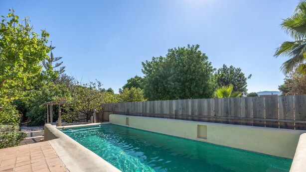 A rectangular swimming pool with clear water, surrounded by a wooden fence and lush greenery. - Rural House 'Sa Caseta Mallorca Studio' with Mountain Views, Shared Pool and Wi-Fi (Algaida)