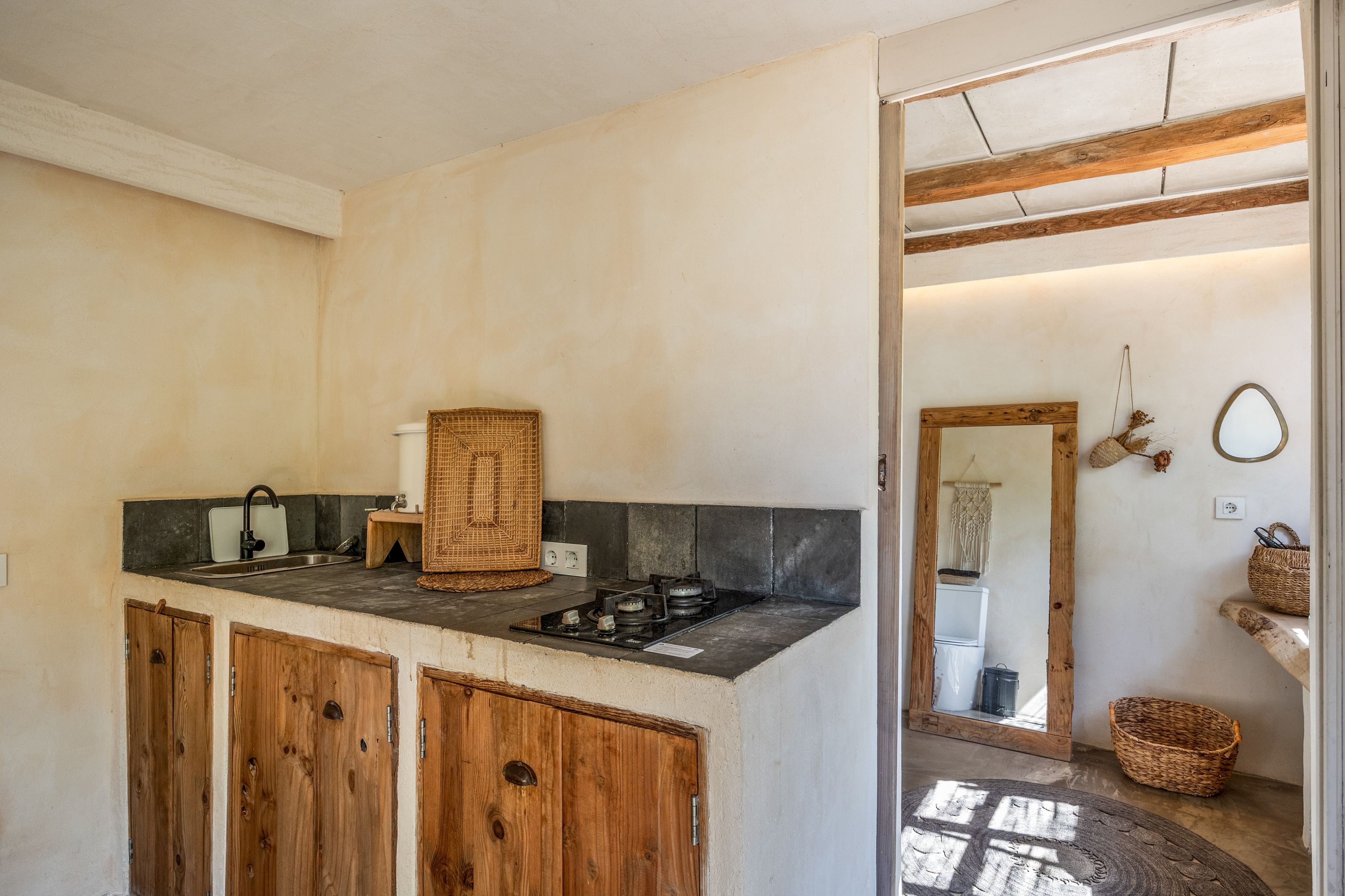 Een keuken met een ingebouwd gasfornuis, houten keukenkastjes en een grote spiegel aan de muur.