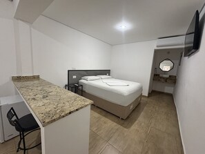 A small, modern room with a bed, a desk, and a chair. - Hotel Paddock (São Paulo)