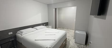 A hotel room with a bed, bedside tables, a flat-screen TV, and a marble floor.