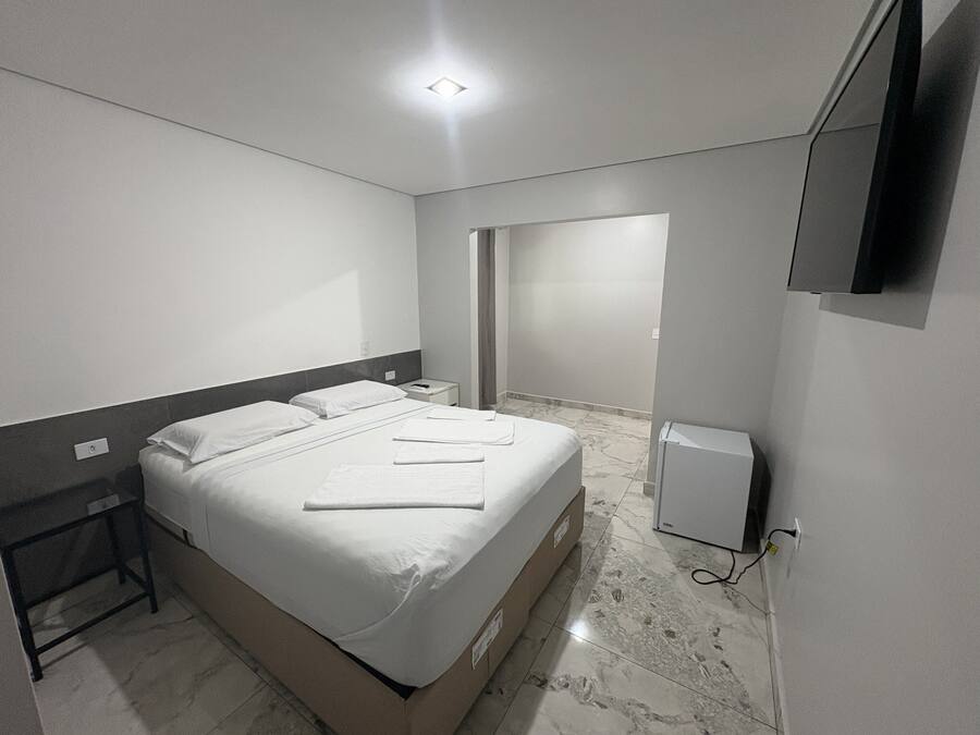 Habitación de hotel con cama, mesitas de noche, televisor de pantalla plana y suelo de mármol.