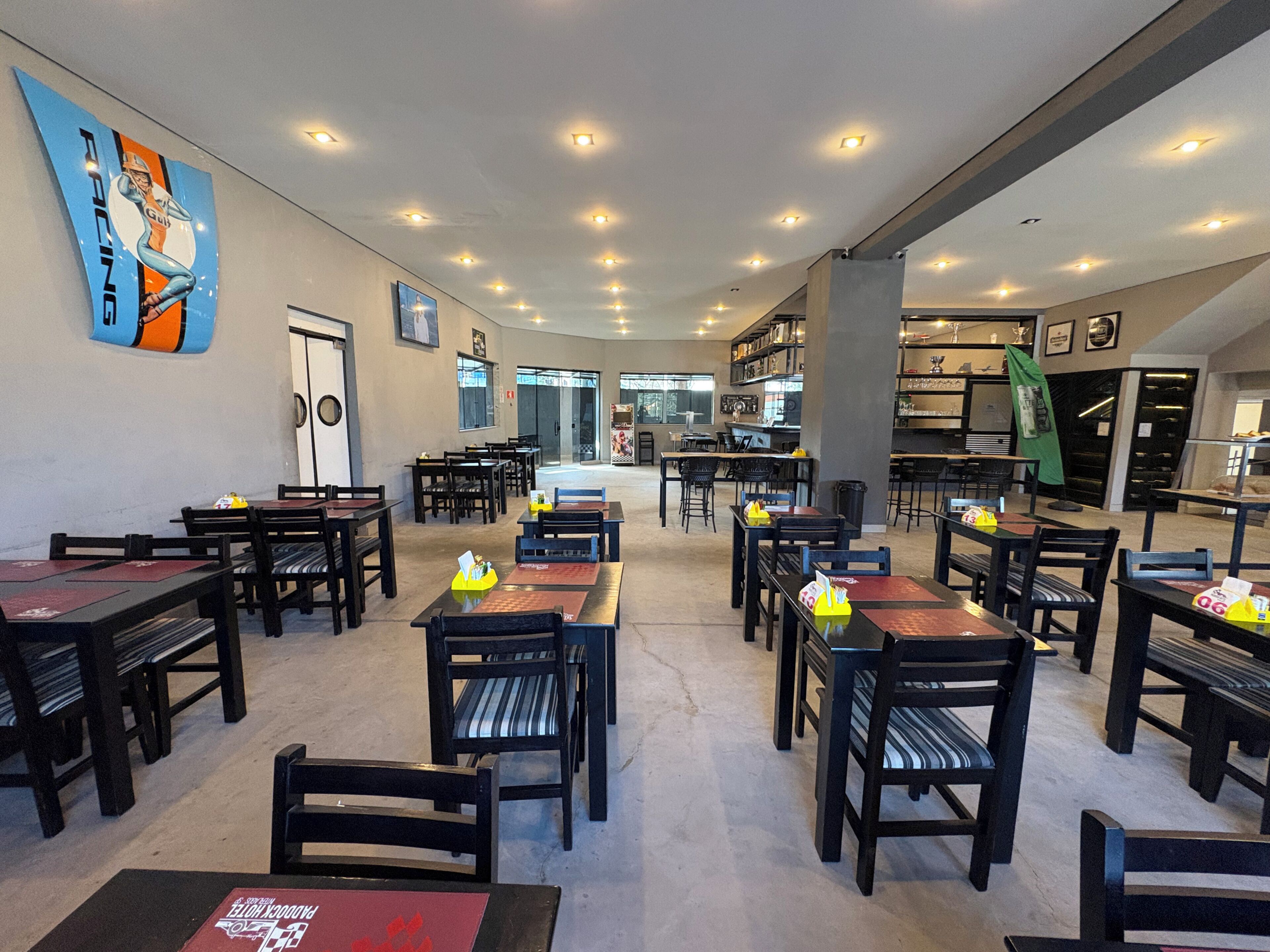 Een restaurant met meerdere tafels en stoelen, een bar en uitzicht op de straat.